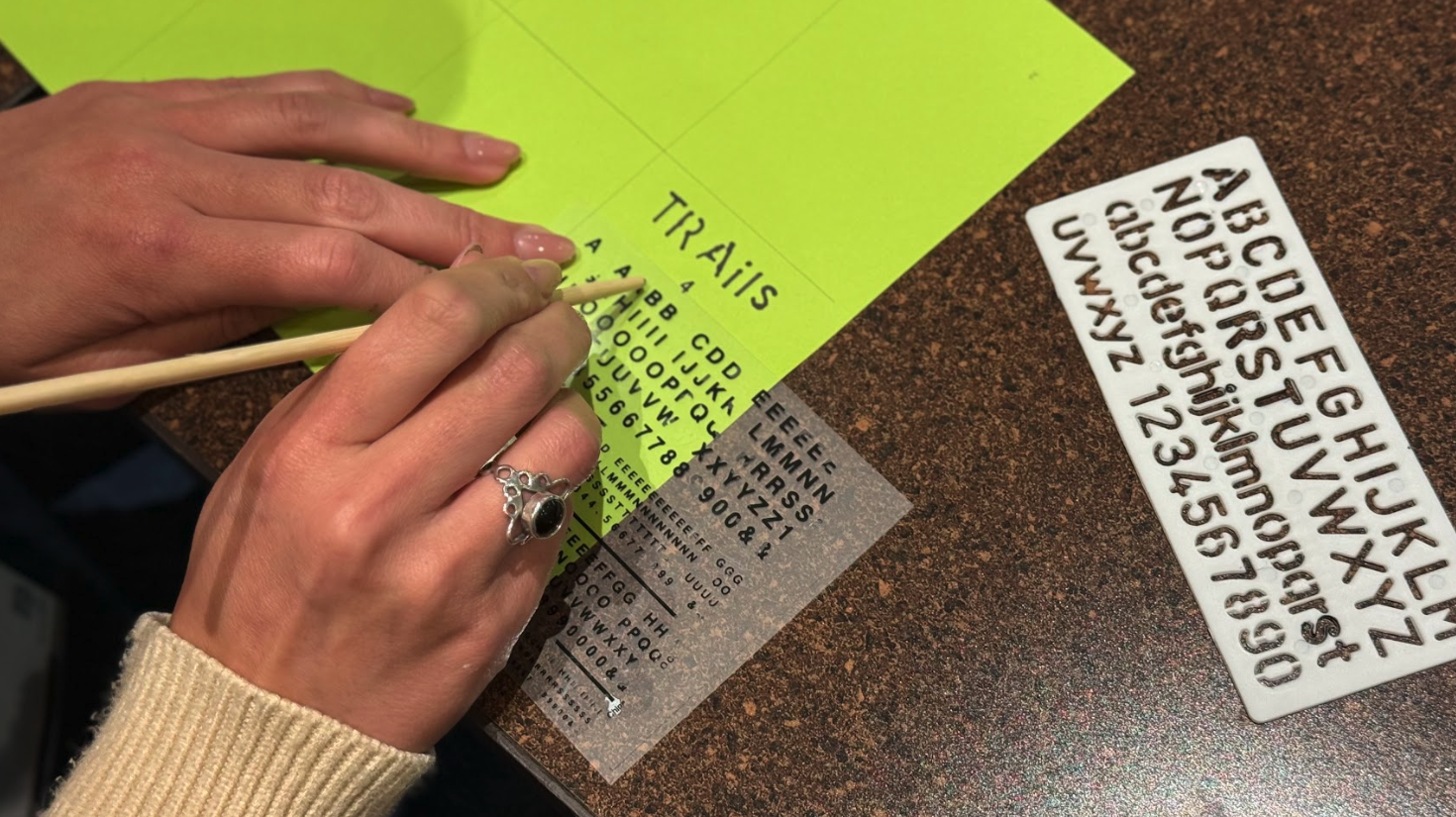 workshop participant using letter stencils to make a trail zine