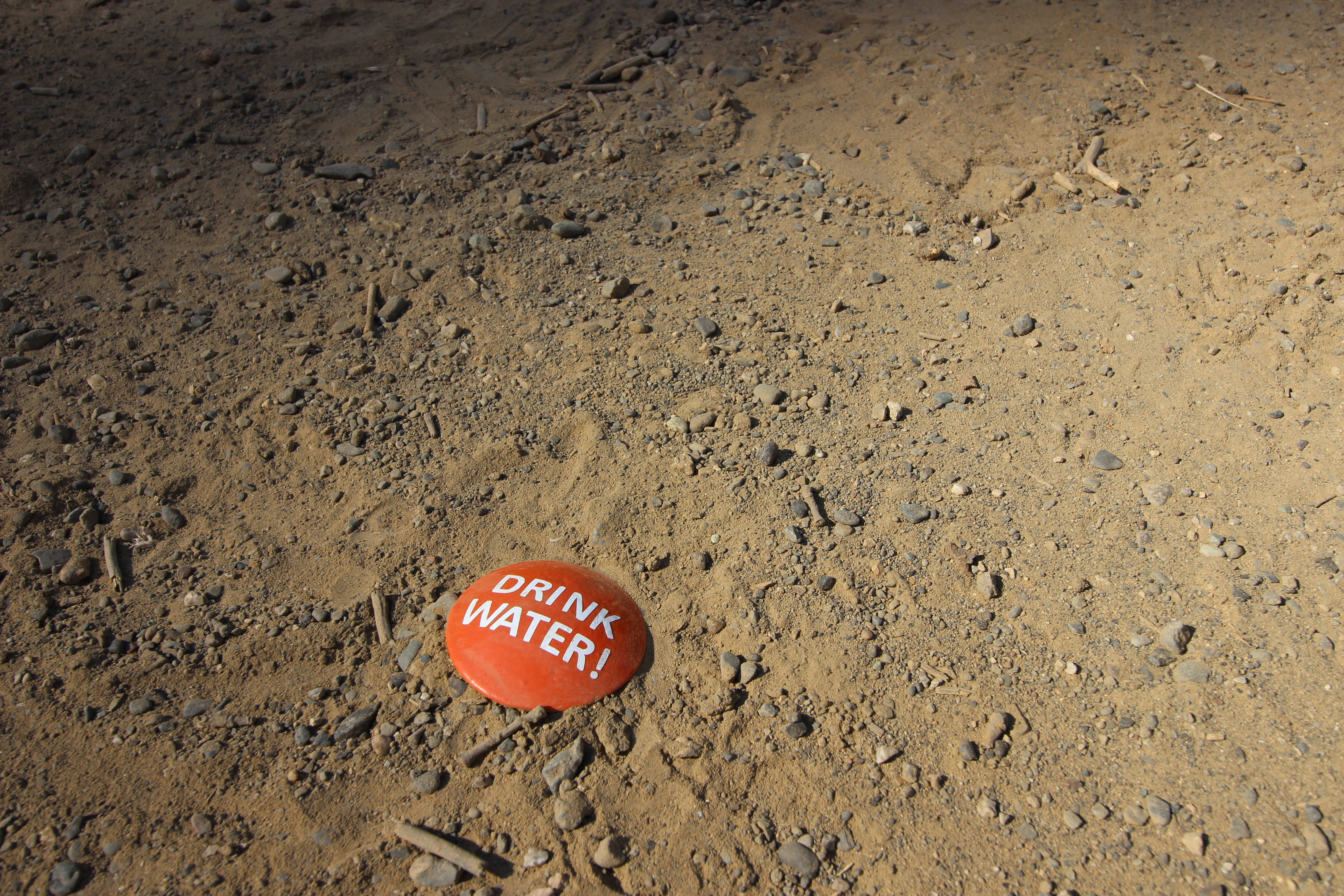 orange DRINK WATER ground stake installed on trail dirt